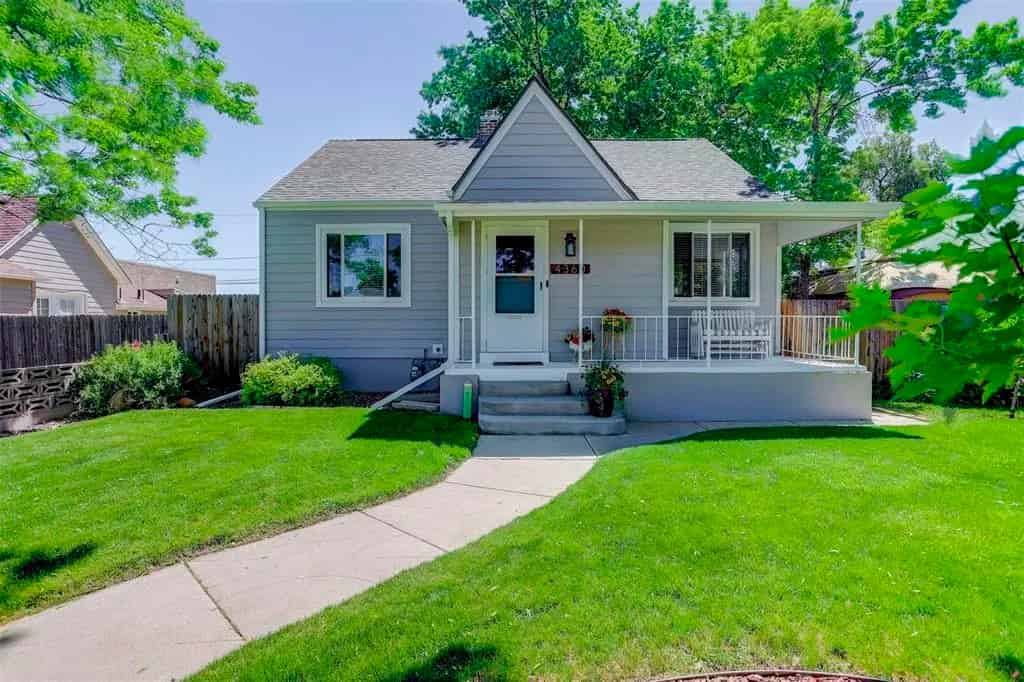 a small house with a white picket and a green lawn