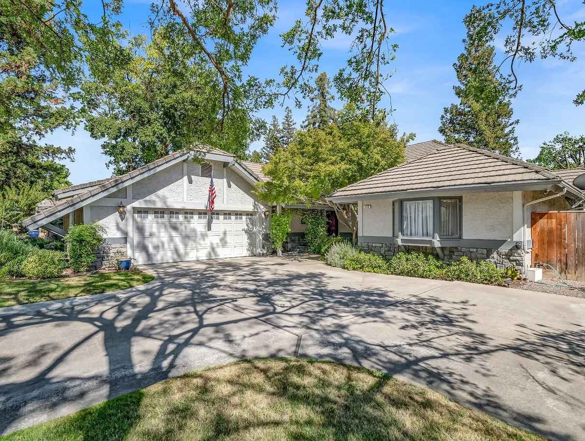 a house with a driveway and trees in the background