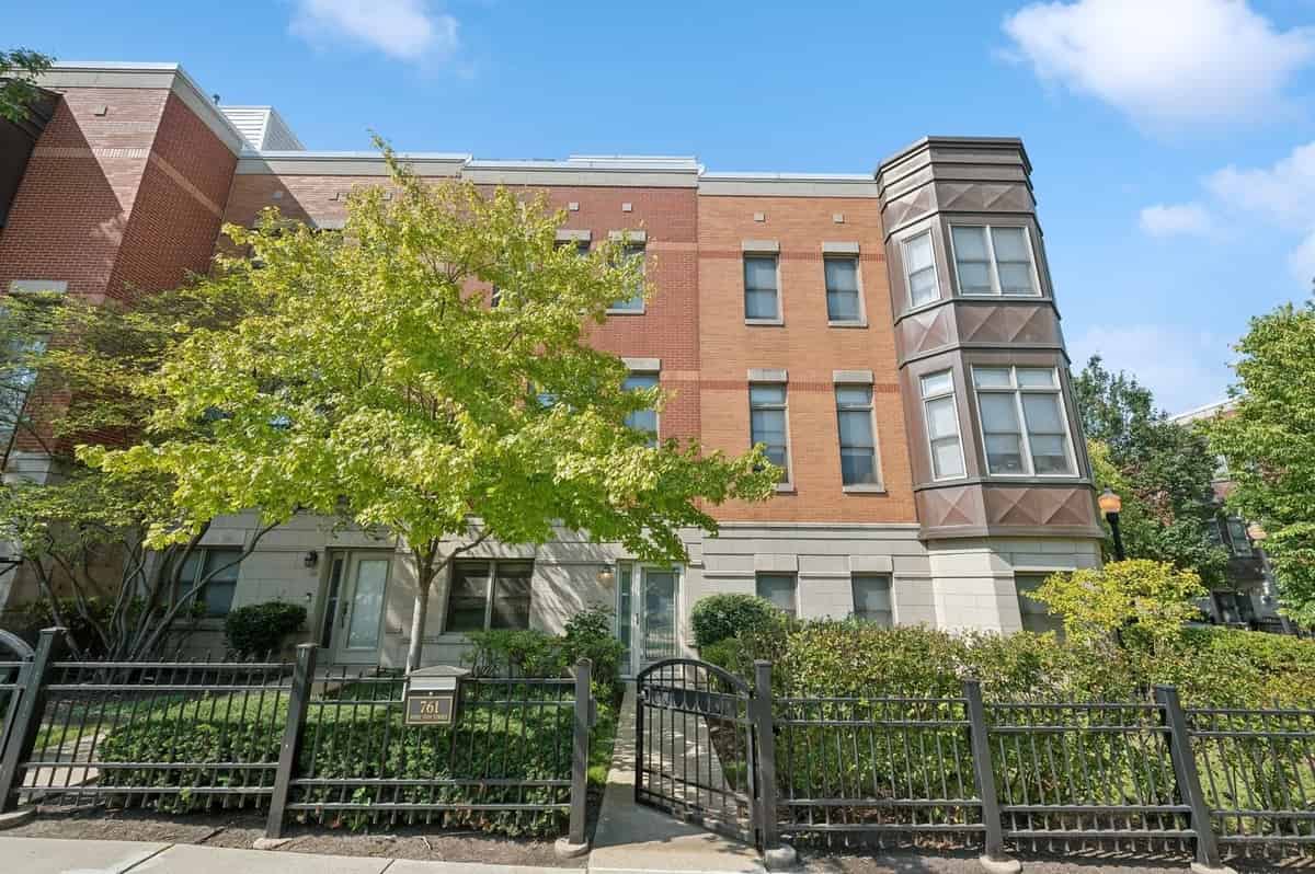 a brick apartment with a fence in front of it