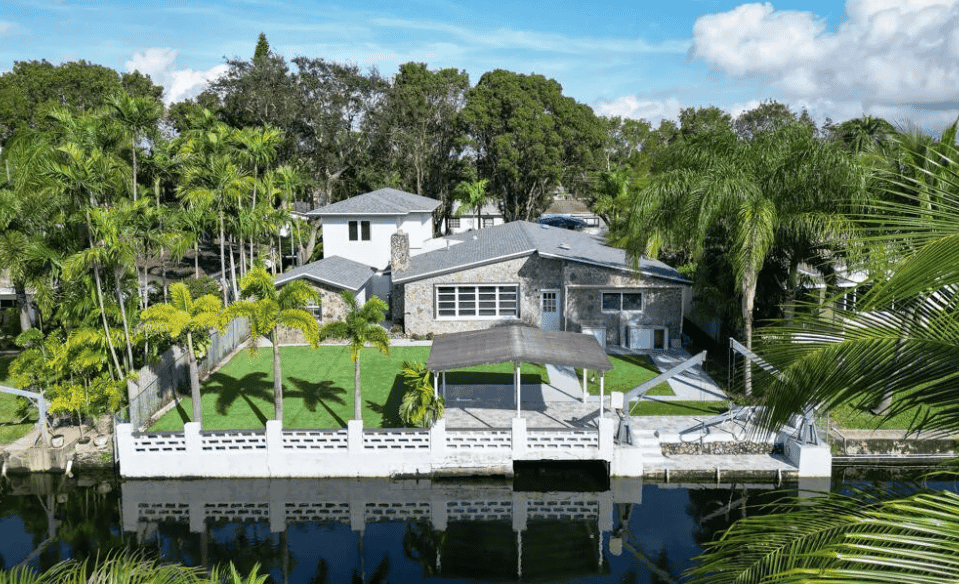 a house on the water with palm trees and a dock