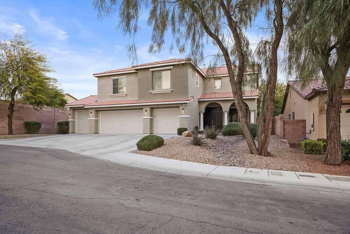 a home in the desert with a driveway and palm trees