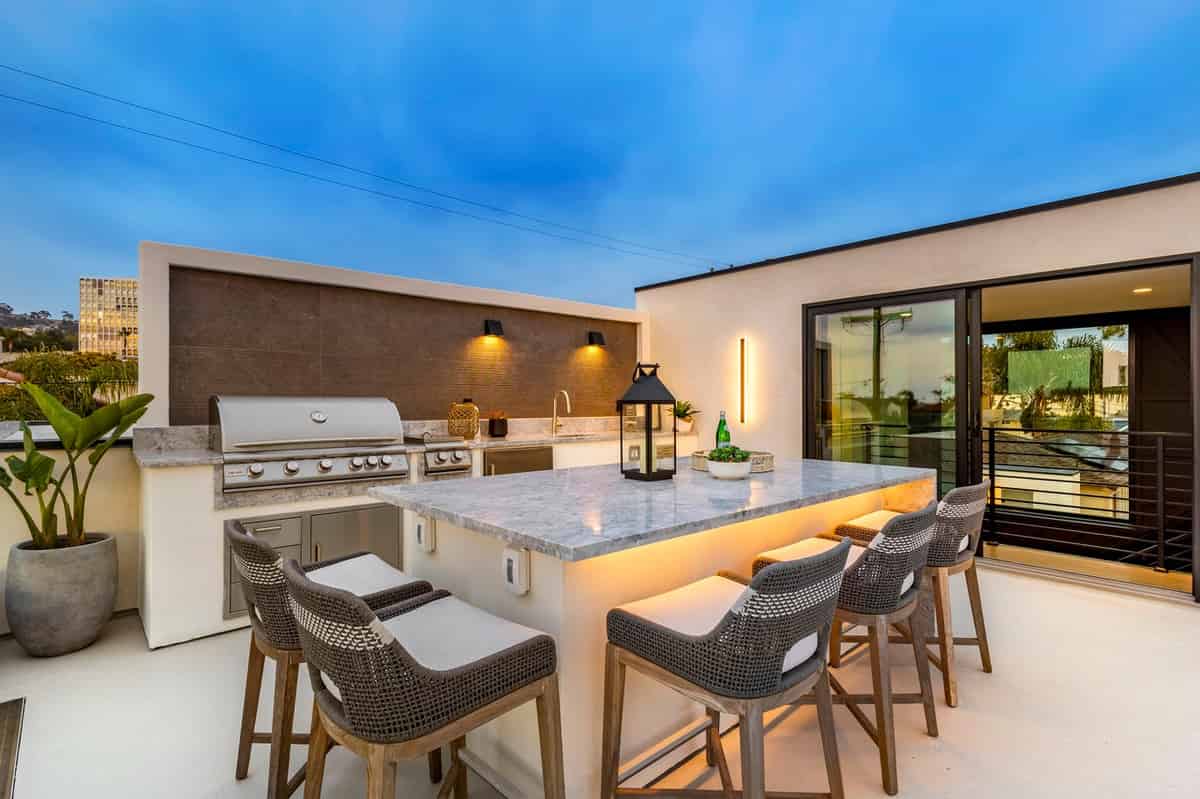 a kitchen with a grill and chairs on the patio
