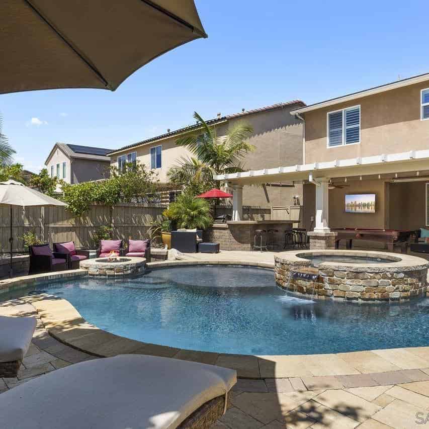 a backyard pool with a fire pit and lounge chairs