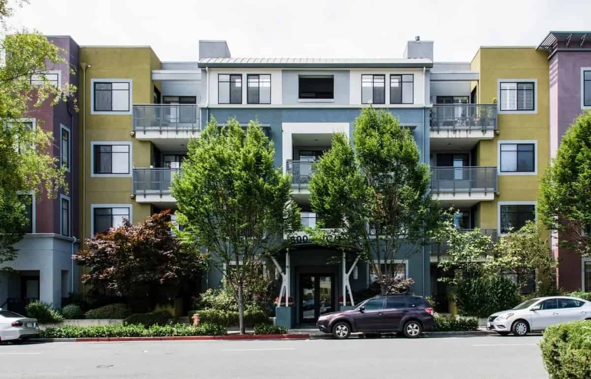 a large apartment building with many trees in front