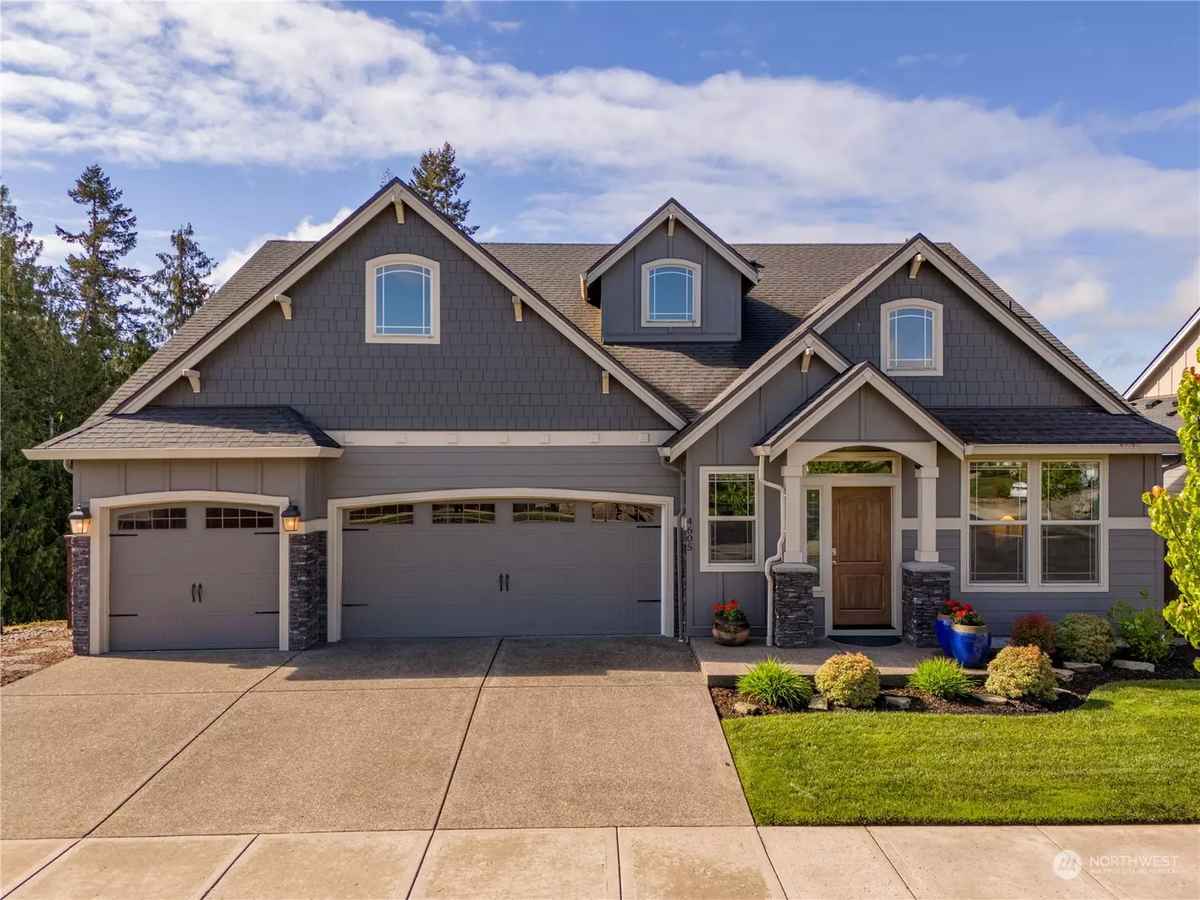 a gray house with a large driveway and a garage