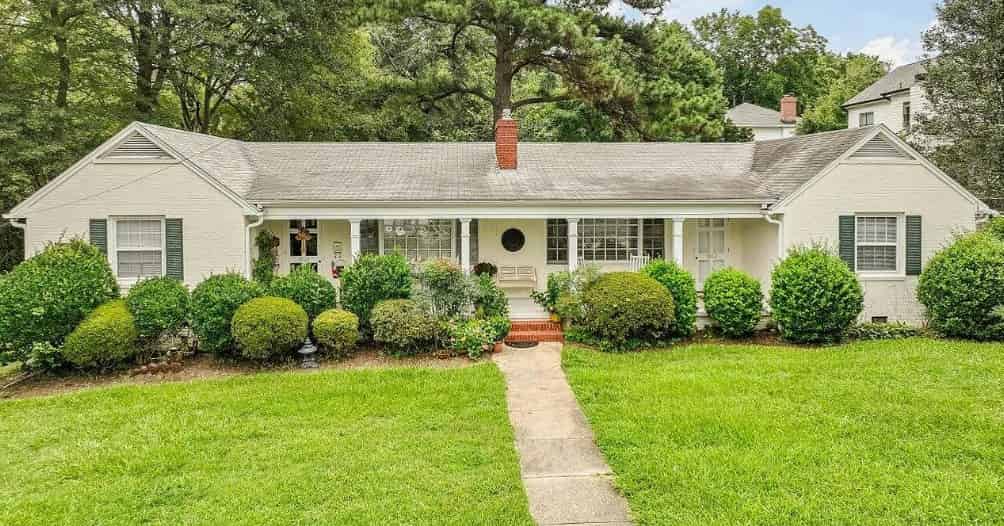 a white house with a green lawn and trees in the background