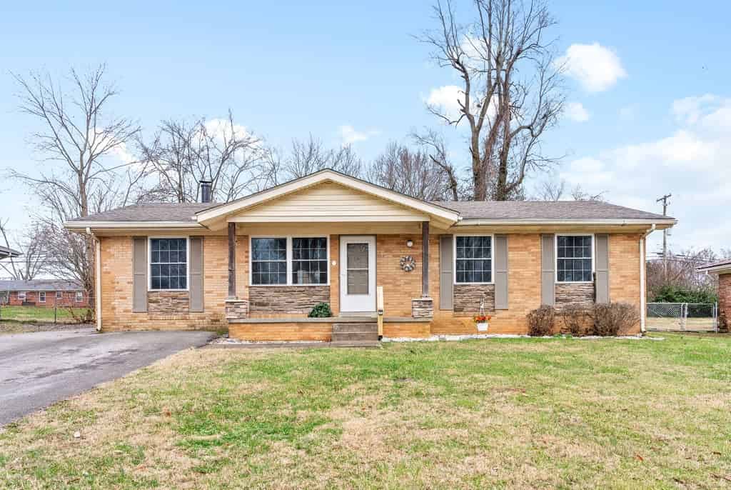 a brick house with a large yard and a driveway