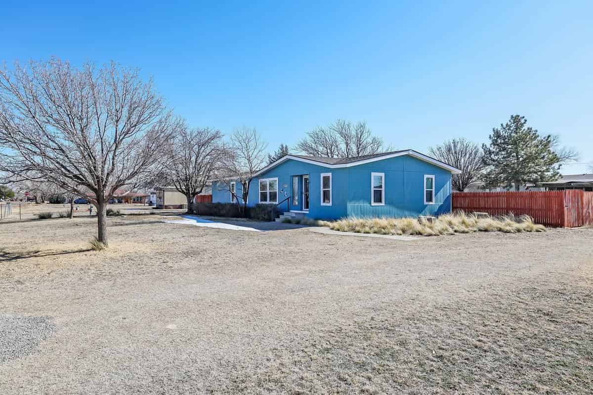 a blue house with a red fence and a tree in the background