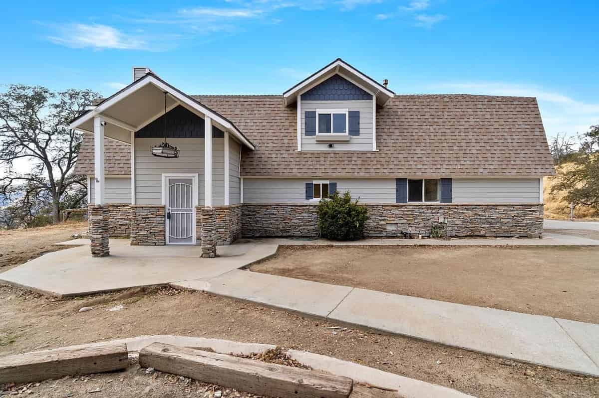 a home with a stone wall and a large driveway