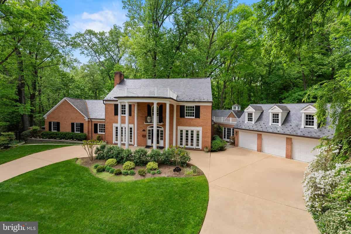 a brick home with a driveway and trees in the background