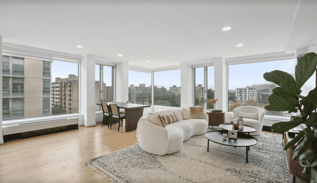 a living room with hardwood floors, a large window, and a white couch